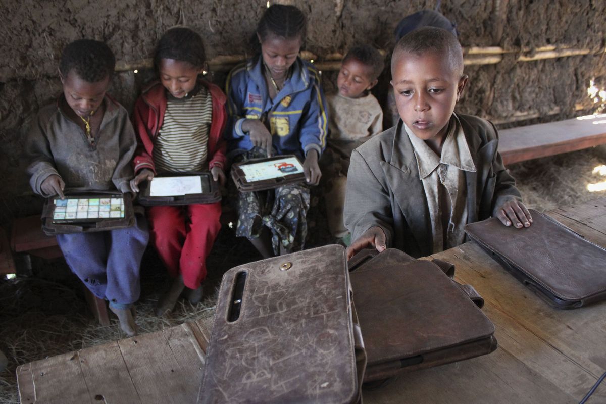 A boy looks for his tablet computer as others play with theirs, given to their village of Wenchi, Ethiopia, by the One Laptop Per Child project. (Associated Press)