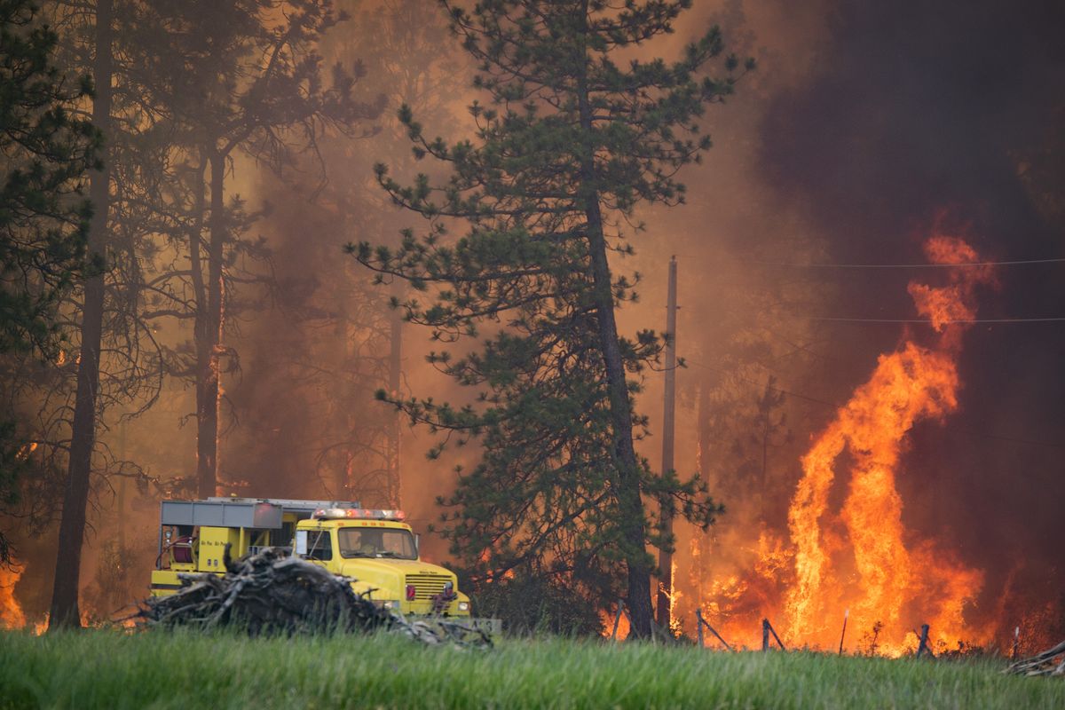 A Spokane County Fire District 3 brush rig works Wednesday at the Fish Lake fire along Scribner Road. Below: A firefighting helicopter drops a load of water on the fire. (Colin Mulvany)
