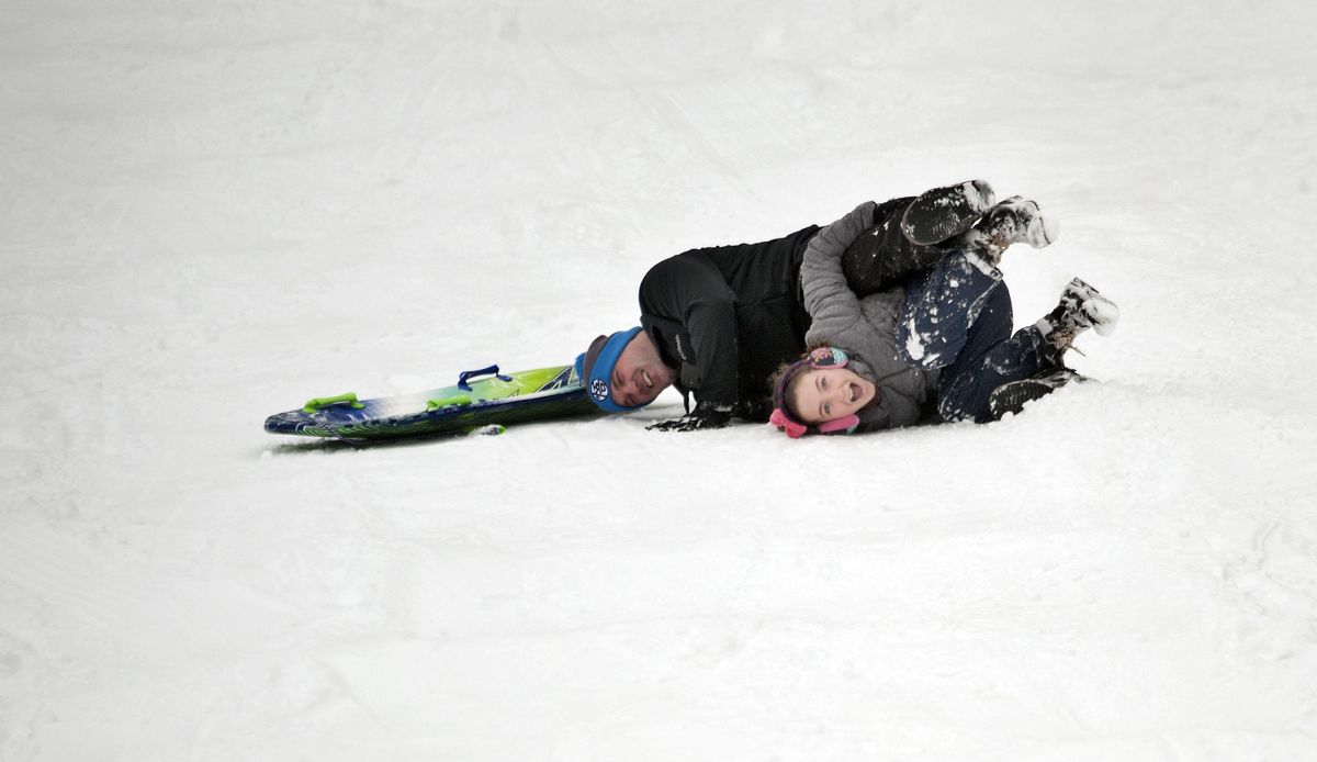 Ten-year-old Aurora Beecher rolls off her sled while trying to hold on to her dad Brody while sledding at Cherry Hill Park in Coeur d