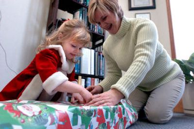 
Richelle Hintz, right, and her daughter Ari, 3, wrap gifts for Kevin Hintz's patients Friday. The Hintzes also gave patients food to prepare a holiday meal. 
 (The Spokesman-Review)