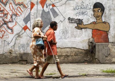 
People pass graffiti Saturday in Rio de Janeiro, where the issue of a gun ban is tied to concerns about drug trafficking.  
 (Associated Press / The Spokesman-Review)