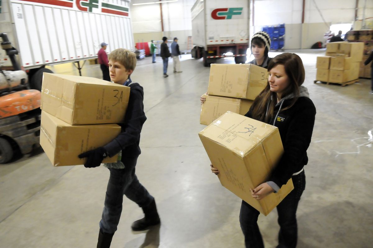 Kyle Kerley, Luke Petersen and Samantha Millsap, Gonzaga Prep students, carry boxes of toys to the storage area after they are unloaded from semitrailers Tuesday at the Spokane County Fair and Expo Center, the site of the Christmas Bureau.  (Jesse Tinsley)