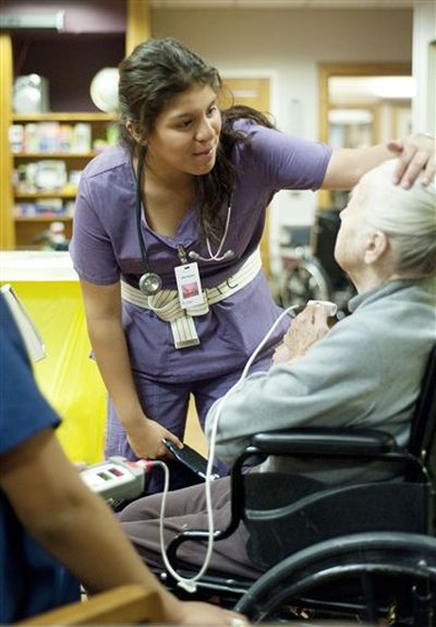 Karen Casillas checks on resident Katherine Wankow on Tuesday, May 22, 2012, in Jackson, Wyo. Casillas is one of five Jackson Hole High School students who spent 36 hours at the nursing home as part of a certified nursing assistant program. (Price Chambers / AP Photo/Jackson Hole News & Guide)