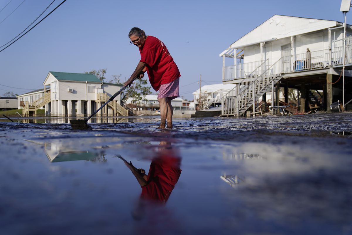 Cindy Rojas cleans mud and floodwater from her driveway in the aftermath of Hurricane Ida, Sunday, Sept. 5, 2021, in Lafitte, La.  (John Locher)