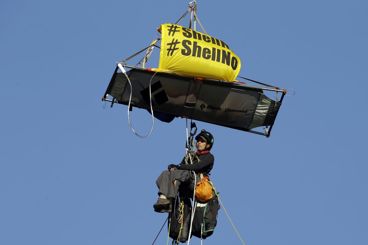 An activist watches while hanging from the St. Johns bridge as the Royal Dutch Shell PLC icebreaker Fennica turns around in Portland on Thursday. (Associated Press)