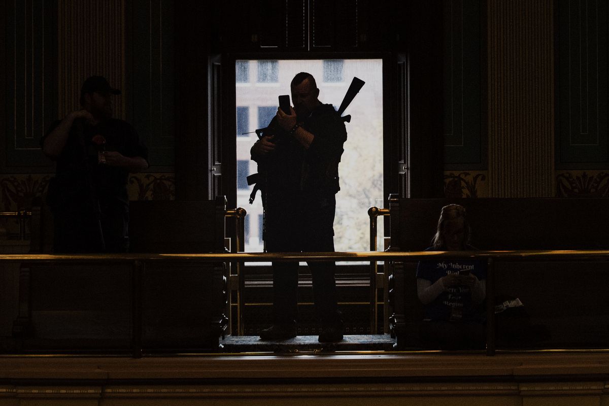 Militia members wait inside the Senate chamber at the Capitol building during the "American Patriot Rally on Capitol Lawn" protest in Lansing, Mich., Thursday April 30, 2020, during the coronavirus outbreak. Experts say far-right groups in the U.S. are taking a more dangerously radical turn as four men go on trial in an alleged scheme to kidnap Michigan