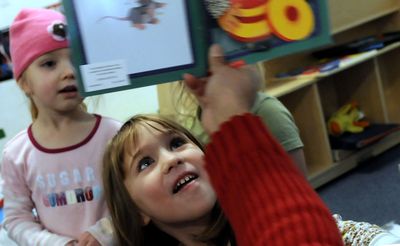 Autumn Tatman, 5, front, checks out the pictures during reading time at Daystar Christian Daycare in Post Falls on Dec 17.  (Kathy Plonka / The Spokesman-Review)