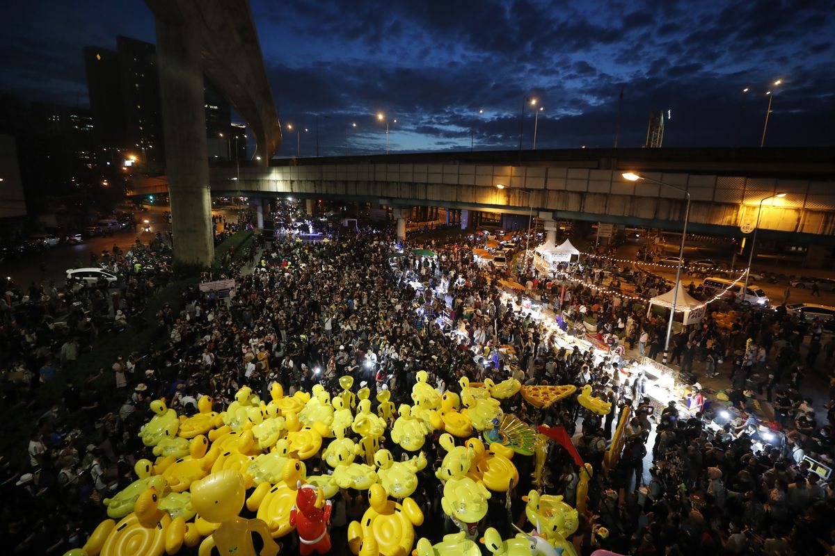 Inflatable yellow ducks, which have become good-humored symbols of resistance during anti-government rallies, are lifted over a crowd of protesters Friday, Nov. 27, 2020 in Bangkok, Thailand. Pro-democracy demonstrators are continuing their protests calling for the government to step down and reforms to the constitution and the monarchy, despite legal charges being filed against them and the possibility of violence from their opponents or a military crackdown.  (Sakchai Lalit)