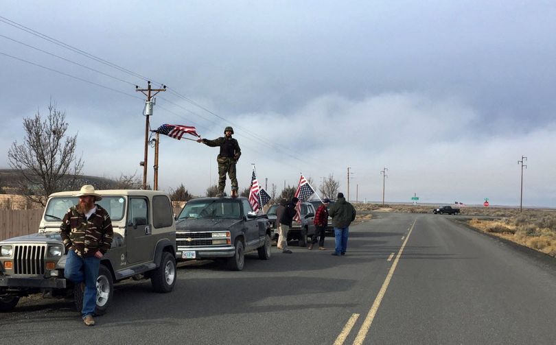People wave American flags near the Malheur National Wildlife Refuge, Thursday, Feb. 11, 2016, near Burns, Ore. The last four armed occupiers of the national wildlife refuge in eastern Oregon said they would turn themselves in Thursday morning, after law officers surrounded them in a tense standoff. (AP Photo/Rebecca Boone)
