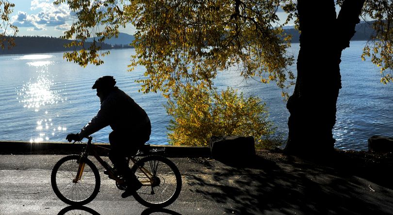 Lapping waves: A cyclist took advantage of the beautiful weather on Tuesday and pedaled along Lake Coeur d’Alene on the Centennial Trail. (Kathy Plonka)