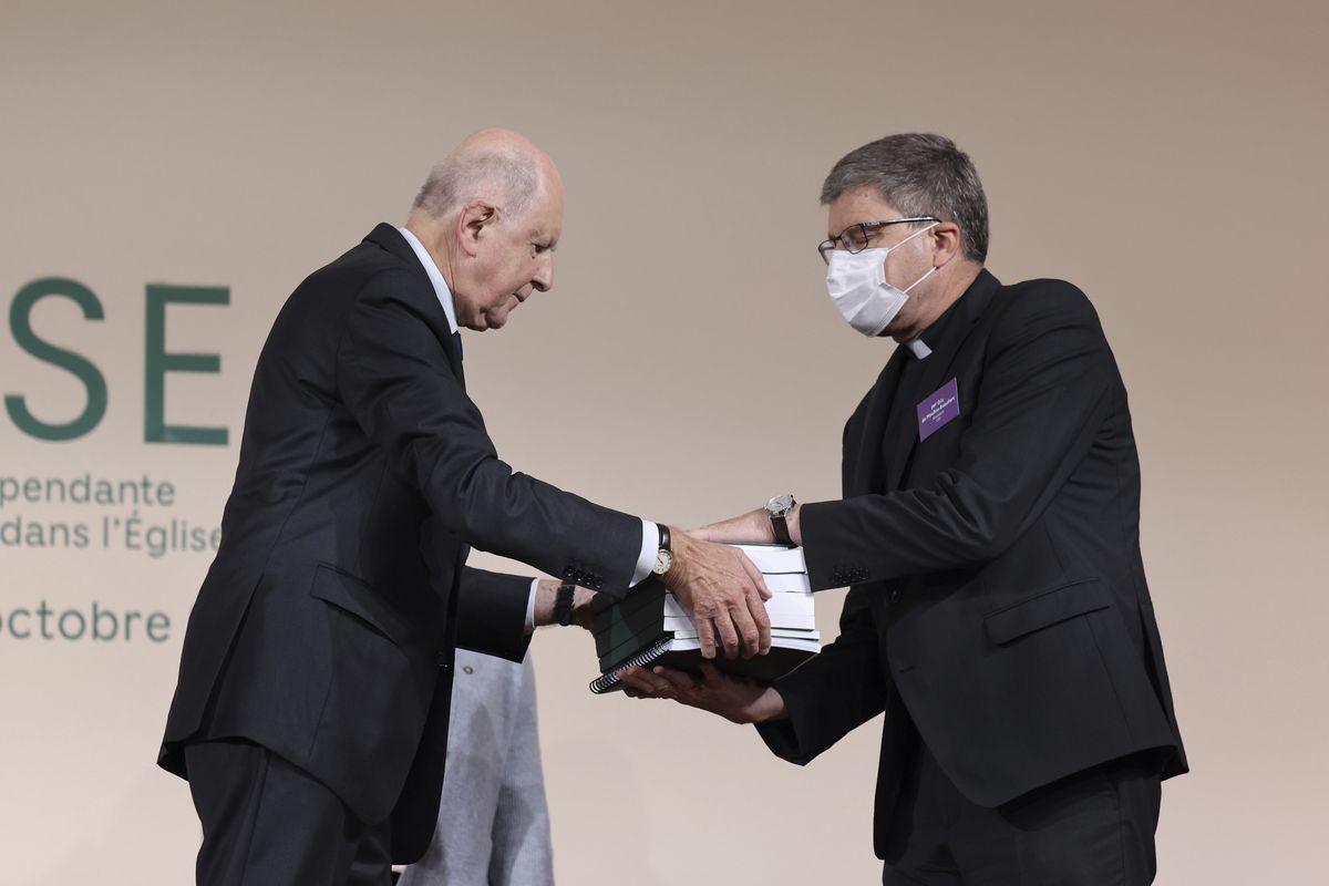 Commission president Jean-Marc Sauve, left, hands copies of the report to Catholic Bishop Eric de Moulins-Beaufort, president of the Bishops