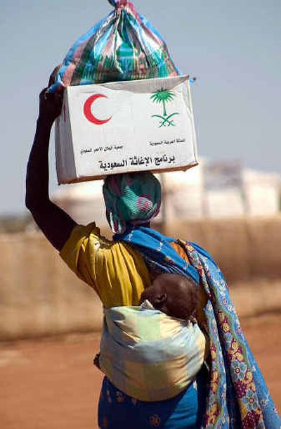 
A displaced Sudanese woman carries her baby on her back and a box of aid provided by the Saudi Relief Agency on Tuesday in Sudan's Darfur region.
 (Associated Press / The Spokesman-Review)