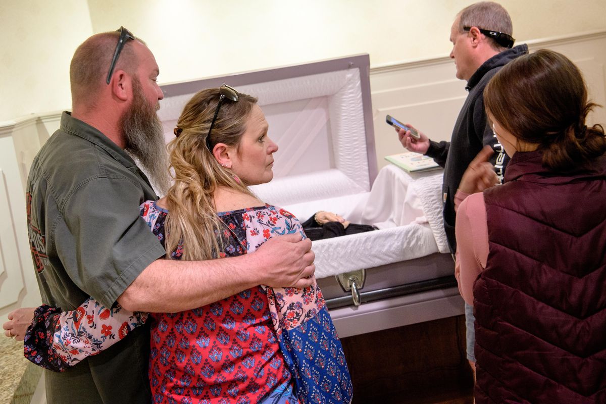 Sean Young, far right, FaceTimes family members into a viewing for their mother LaVonne Young as his sister Michelle Lampert, second left, looks to her daughter Mackenzie Wells, second right, as she is embraced by her husband Dino Lampert, on Thursday at Yates Funeral Home in Coeur d