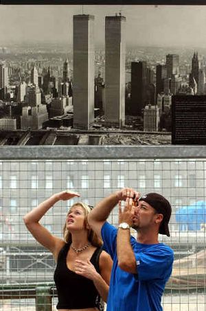 
Michael Keeley, right, and Lisa Theis, both of Sacramento, Calif., stand below a poster of the World Trade Center twin towers as they visit ground zero in New York.
 (Associated Press photos / The Spokesman-Review)