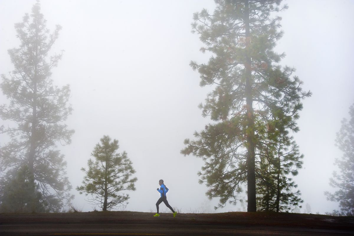 A lone runner makes her way along the densely fog-covered bluff on Spokane’s High Drive on Tuesday. (Dan Pelle)