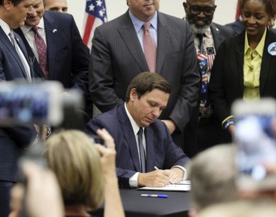 In this Friday, June 14, 2019 photo, Florida Gov. Ron DeSantis signs the Sanctuary City bill at the Okaloosa County, Fla., commission chambers in Shalimar Fla. The bill requires all law enforcement agencies in Florida to cooperate with federal immigration authorities. U.S. District Judge Beth Bloom on Tuesday, Sept. 21, 2021, rejected parts of the 2019 law banning local government sanctuary policies and requiring local law enforcement to make their best efforts to work with federal immigration authorities.  (Michael Snyder)