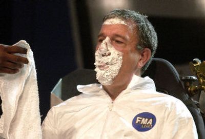 
Horizon Middle School Principal Dennis Rusca licks cream from a pie he rode into while on a hover chair during the FMA Live! education concert at Horizon Middle School in Spokane Valley on Thursday. 
 (Liz Kishimoto / The Spokesman-Review)