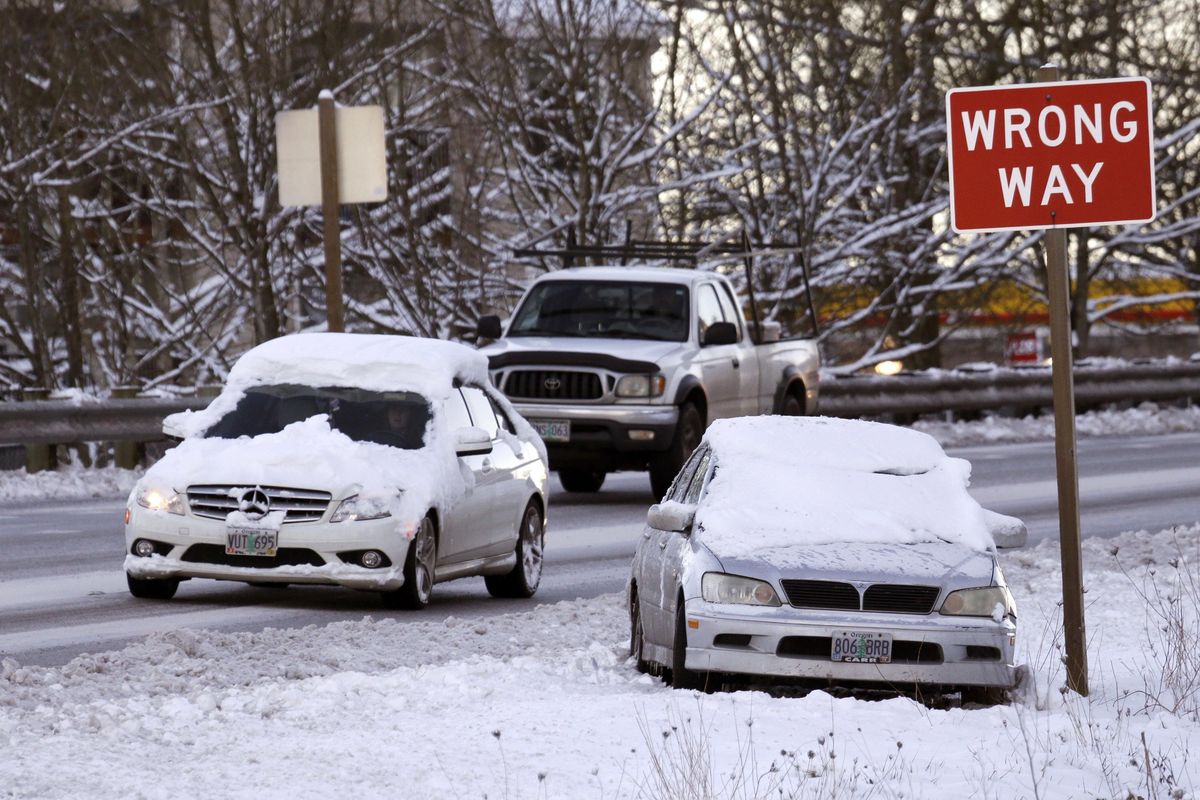 Motorists drive past a stranded car along Highway 99W in King City, Ore., Thursday, Jan. 12, 2017. (Don Ryan / Associated Press)