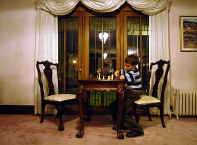 
John Ogden, 9, plays a game of chess in the living room. The glass doors are original to the house.
 (Photos by Liz Kishimoto/ / The Spokesman-Review)