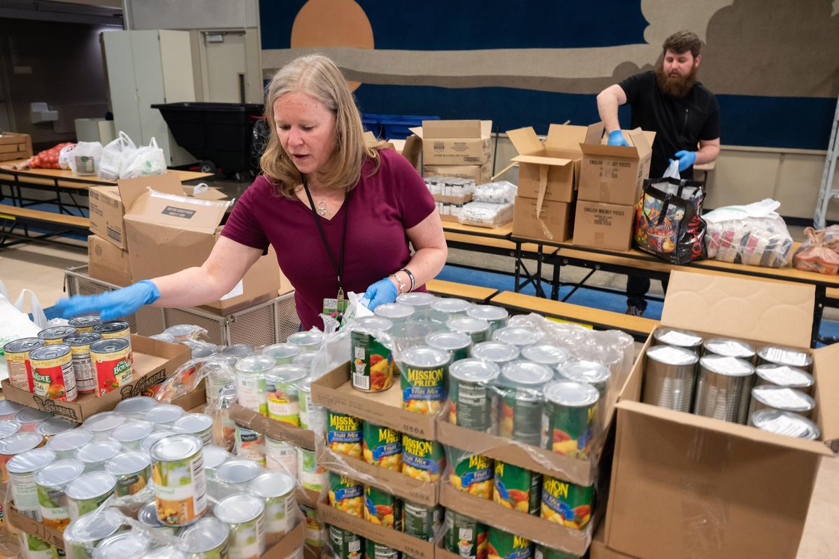 Family resource coordinators with The Zone Project, Amy McColm and Nathan Hamilton, sort donated food to be distributed to families on April 10 at Bemiss Elementary School. (Colin Mulvany / The Spokesman-Review)