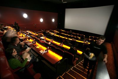 A waiter delivers a meal before a movie in an auditorium within the Fork & Screen wing of the AMC Studio 30 complex in Olathe, Kan. This is one of the 11 redesigned auditoriums at the complex that offer – for a premium – exclusive seating, padded recliners, alcoholic drinks and a full kitchen making Parmesan fries, Thai coconut chicken and Darkiccino chocolate brownies. (Associated Press / The Spokesman-Review)