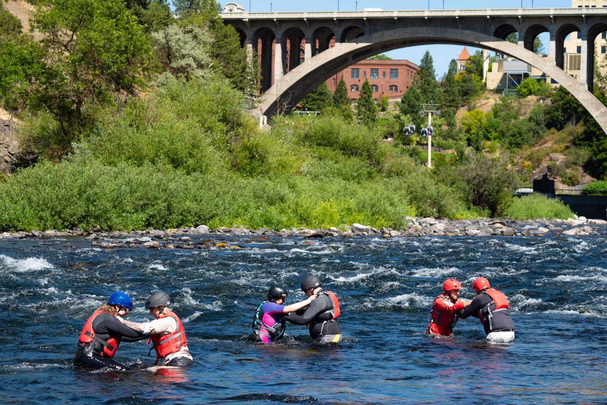 As part of the Wilderness Medical Society conference in Spokane this week, a swiftwater rescue class for medical professionals was held Tuesday in the Spokane River rapids below the Monroe Street Bridge. Here, paddlers learn to perform an assisted wade in fast-moving shallow water.  (COLIN MULVANY/THE SPOKESMAN-REVI)