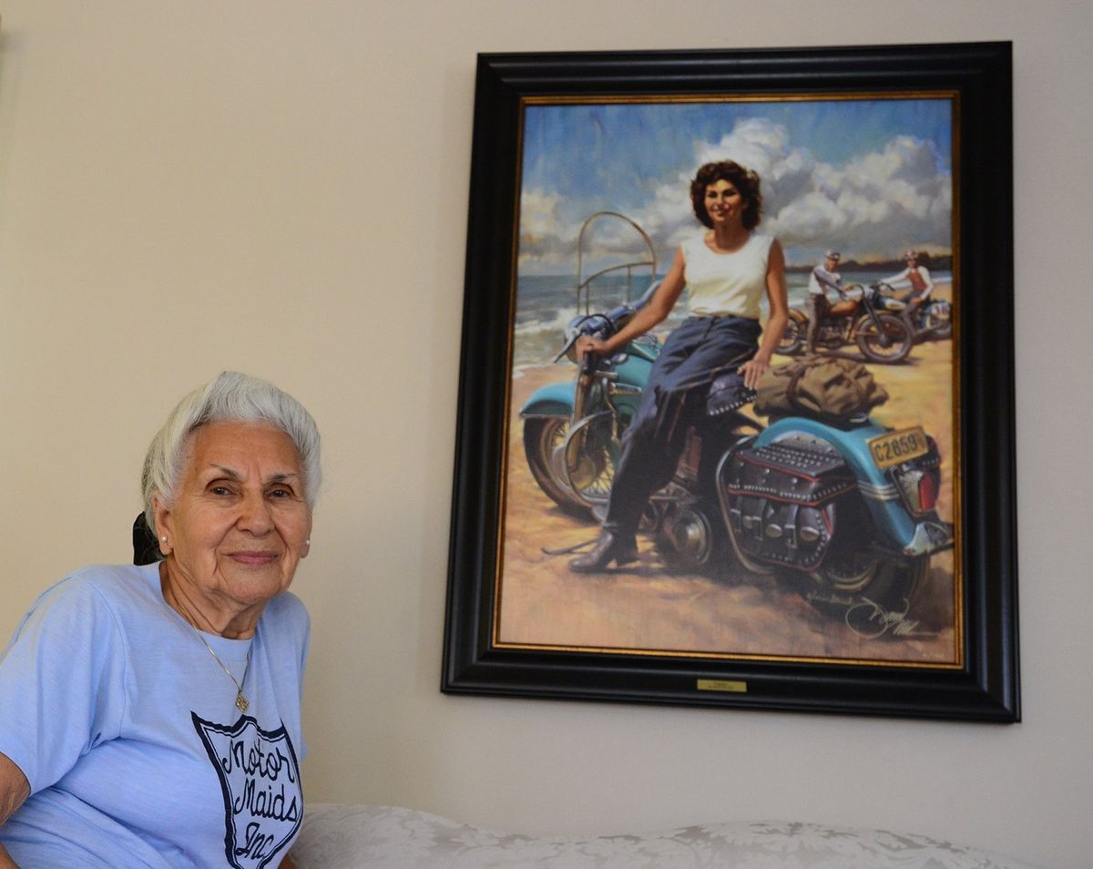 Gloria Struck poses by a painting based on a 1950 photo of her on a Harley. Struck has ridden motorbikes since the 1940s.