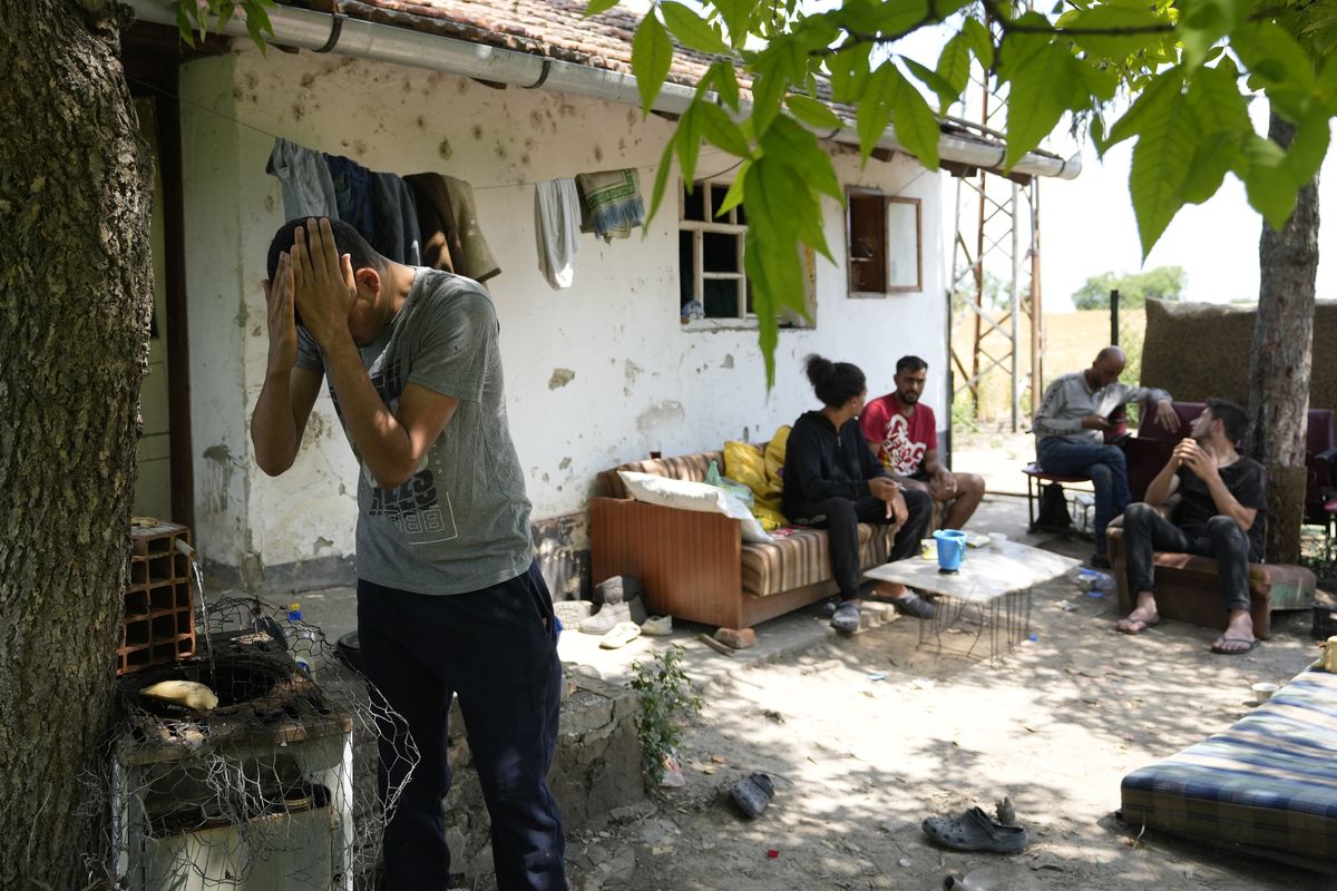 Migrants rest in front of an abandoned house in the village of Majdan, Serbia, Thursday, July 22, 2021. Empty or abandoned houses serve as temporary homes to people who fled their own homes in the Middle East, Africa or Asia with an aim to start a new life somewhere else.  (Darko Vojinovic)