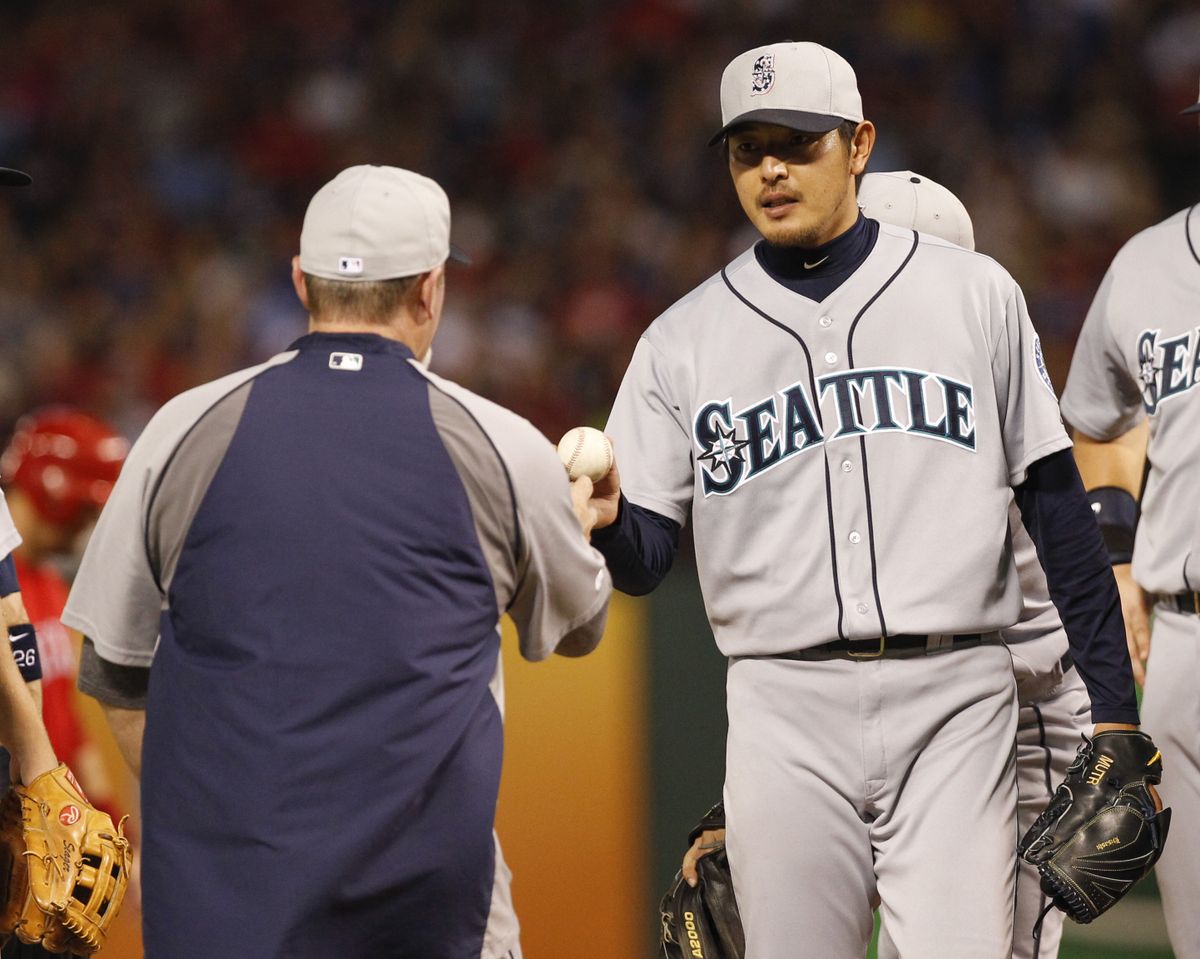 M’s manager Eric Wedge, left, takes ball from starter Hisashi Iwakuma in seventh. (Associated Press)