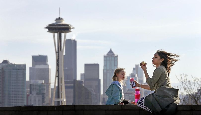 Nora Kennelly, 3, picnics with her nanny, Ty Messiah, in the sun atop a wall overlooking the Space Needle and downtown Seattle on Monday. Seattle is among the most densely populated cities in the country. See story below. (Elaine Thompson / Associated Press)