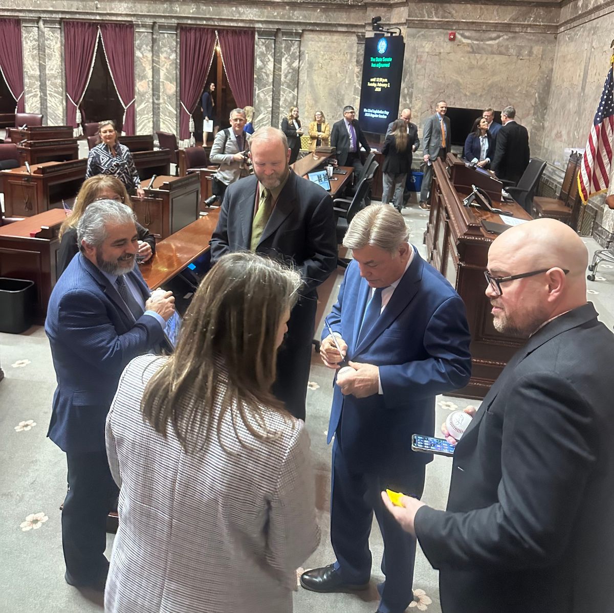 Mariners Broadcaster Rick Rizzs signs autographs in the Senate chamber after lawmakers unanimously adopted a resolution to recognize the team on Monday, Feb 2.  (Mitchell Roland / The Spokesman-Review)