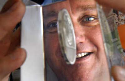 
Don Kardong looks through an encased Bloomsday medal at race headquarters. Kardong is in charge of the annual event that draws thousands of runners to downtown Spokane. 
 (Brian Plonka / The Spokesman-Review)