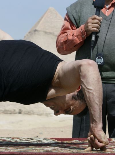 Egyptian Mohammed Ali Zinhom, 25, attempts a new Guinness World Record for doing push ups on the 2 fingers of his right hand only, in front of the historical site of the Giza Pyramids, Egypt, Monday, March 8, 2010. Zinhom recorded 46 push ups in 49 seconds. At right an Egyptian referee monitors the push ups. (Amr Nabil / Associated Press)
