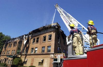 
Spokane firefighters Bob Smith, right, and Dave Batty watch Carl Raymond atop a ladder as the crew from Station 11 pour water upon the collapsed roof of the Lloyd building at Monroe and Mansfield in August 2005. Batty was reinstated in 1995. 
 (File / The Spokesman-Review)