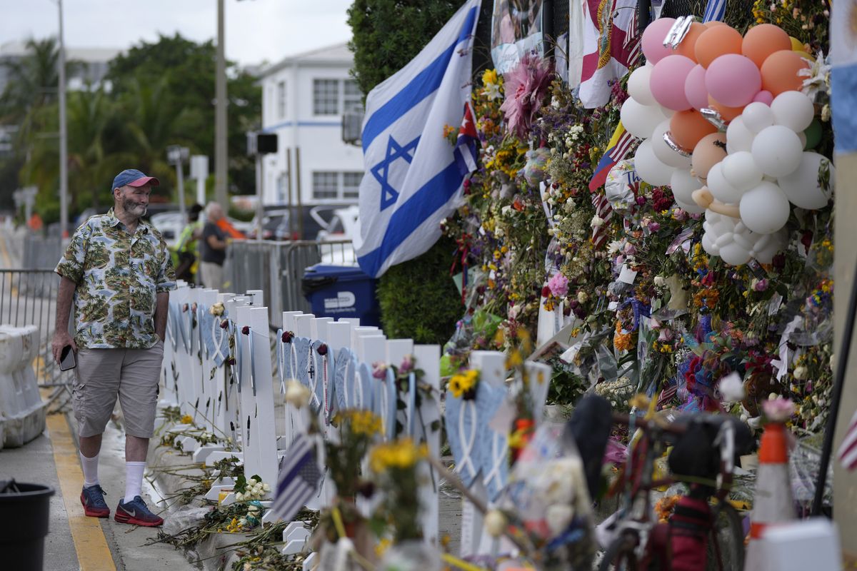 Peter Martin, of New York, who was in Miami visiting his brother, pays his respects at a makeshift memorial for the victims of the Champlain Towers South building collapse, on Monday, July 12, 2021, in Surfside, Fla.  (Rebecca Blackwell)