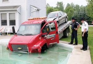 Sgt. Kevin Locicero, left, and Capt. Bruce Elliot, of the Niagara County Sheriff’s Department, examine a truck that drove into a pool in Lockport, N.Y., on Thursday. Police said the driver was juggling two cell phones. (Associated Press / The Spokesman-Review)