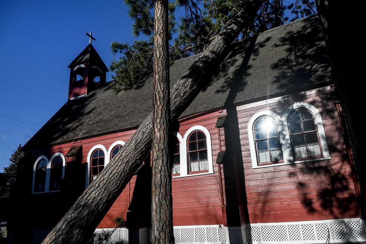 A tree leans on the roof of Fort Sherman Chapel in Coeur d’Alene during the wind storm on Wednesday. The chapel was built in 1880 by the U.S. Army.  (Kathy Plonka/The Spokesman-Review)