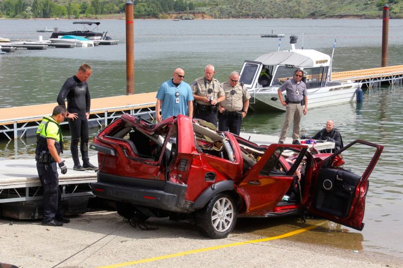 Ada County Sheriff's Deputies and the Boise Fire Department dive team stand by the wreckage of an SUV driven by a 40-year-old Boise woman that plunged off a cliff into the Lucky Peak Reservoir Thursday, June 2, 2016, in Boise, Idaho. Divers with the Boise Fire Department recovered the bodies of two girls, ages 12 and 6, and the body of a 10-year-old boy from the vehicle, which was about 40 feet below the surface Thursday morning, according to the Ada County Sheriff's Office. A witness saw the SUV accelerate from the side of the road to go over the cliff, the sheriff's office said. (Patrick Orr/Ada County Sheriff's Office via AP) 