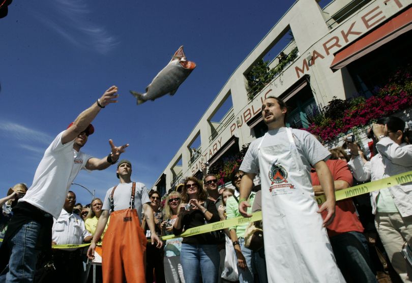 ORG XMIT: NY139  FILE -  In this Aug. 17, 2007 file photo, Erik Espinoza, right, and Anders Miller, center, both of Pike Place Fish Market, look on as J.J. Swanton, left, throws a fish in the salmon-tossing contest held in honor of the 100th anniversary of the Pike Place Market in Seattle. (AP Photo/Ted S. Warren, File) (Ted Warren / The Spokesman-Review)