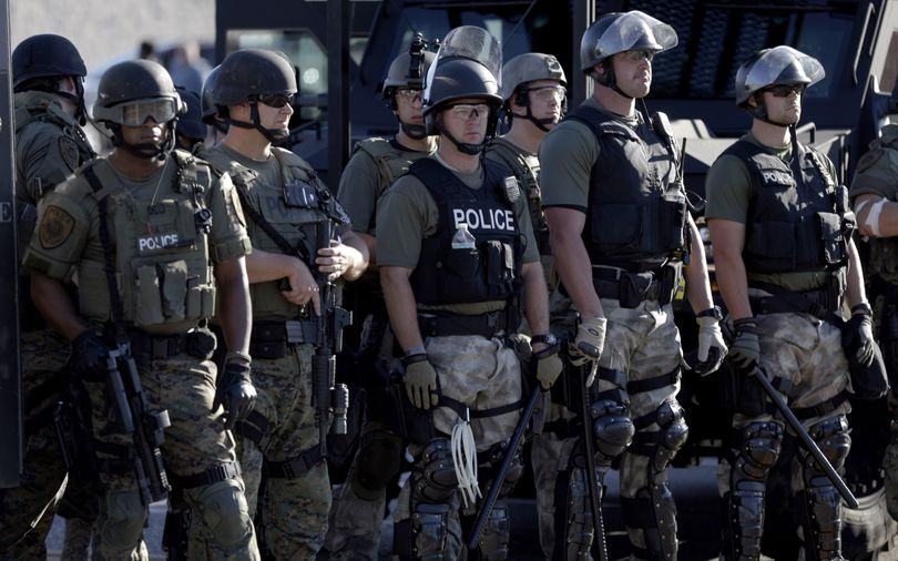 Police in riot gear watch protesters in Ferguson, Mo., on Wednesday. (Associated Press)