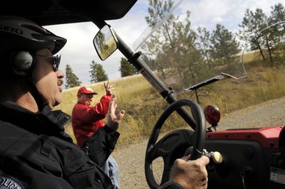 Post Falls Police Department volunteer Vern Ward waves to a man walking along Centennial Trail in Post Falls from one of the department’s all-terrain vehicles, or “Rhinos,” last Thursday.  (Kathy Plonka / The Spokesman-Review)