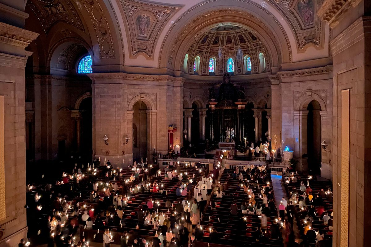 Hundreds of people light candles at the beginning of the Easter Vigil Mass at the Cathedral of St. Paul in St. Paul, Minn., on Saturday, April 16, 2022. For many U.S. Christians, this weekend marks the first time since 2019 that they will gather in person on Easter Sunday, a welcome chance to celebrate one of the year's holiest days side by side with fellow congregants.  (Giovanna Dell'Orto)