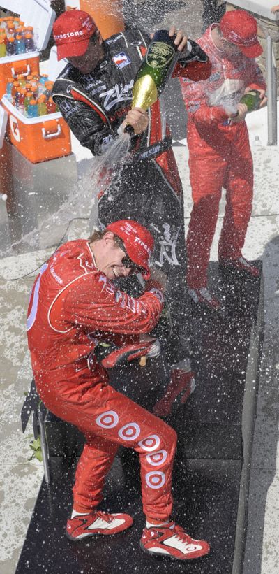 Winner Justin Wilson sprays champagne on Scott Dixon. (Associated Press / The Spokesman-Review)