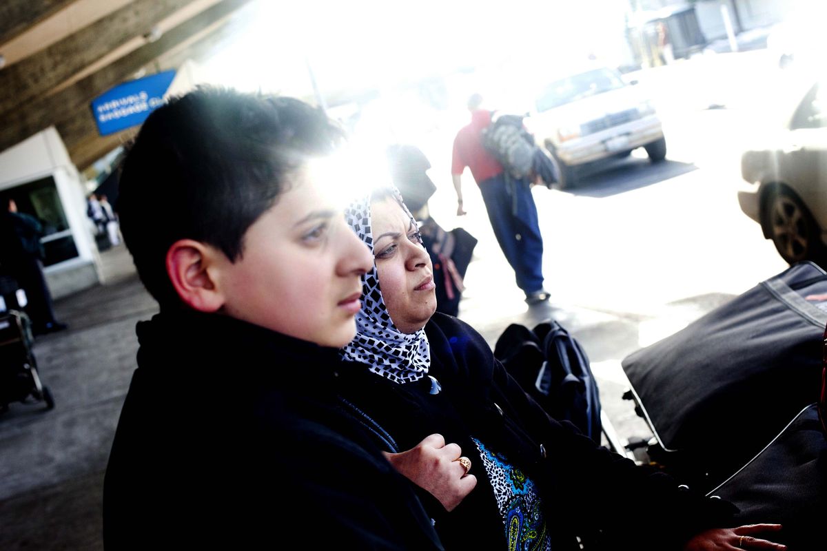 Yousif Sadoon and his mother, Samah Mohammed, await a World Relief van after arriving at Spokane International Airport. (Tyler Tjomsland)