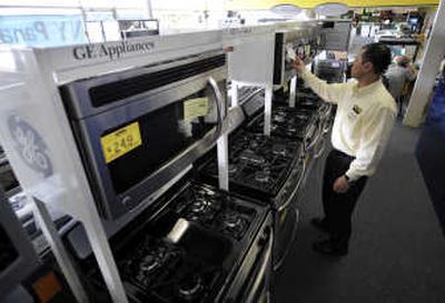 Salesman Hank Pham puts a price tag on a GE microwave Tuesday in the appliances section of Howard's Appliance and Big-Screen Superstore in San Gabriel, Calif. General Electric Co. lowered its outlook for the full year Friday. Associated Press
(Associated Press / The Spokesman-Review)