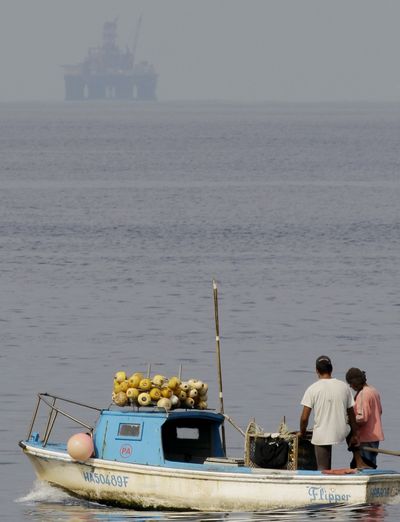 An oil rig floats in the distance as fishermen work in Havana Bay, Cuba, on Thursday. The rig will start exploratory drilling off Cuba’s northern coast. (Associated Press)