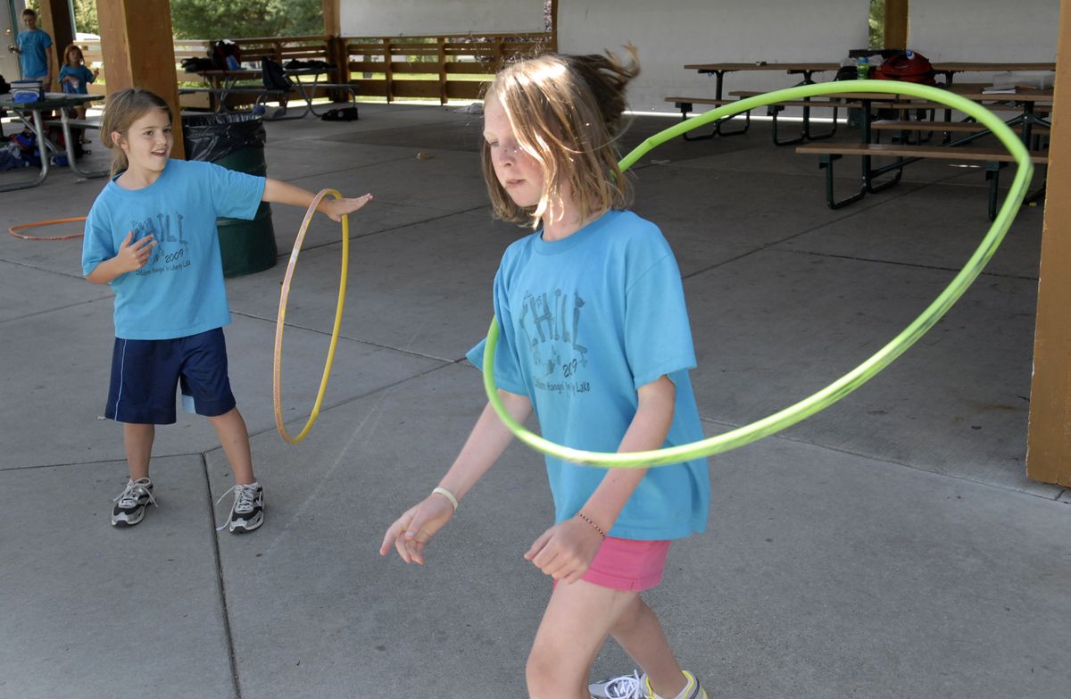 Sydney Bruce, right,  11, and Carissa Ball, 9, practice hula hoop tricks at Children Hangin’ In Liberty Lake Day Camp at Pavillion Park. The popular day camp is sold out this summer and has a waiting list. (J. BART RAYNIAK / The Spokesman-Review)