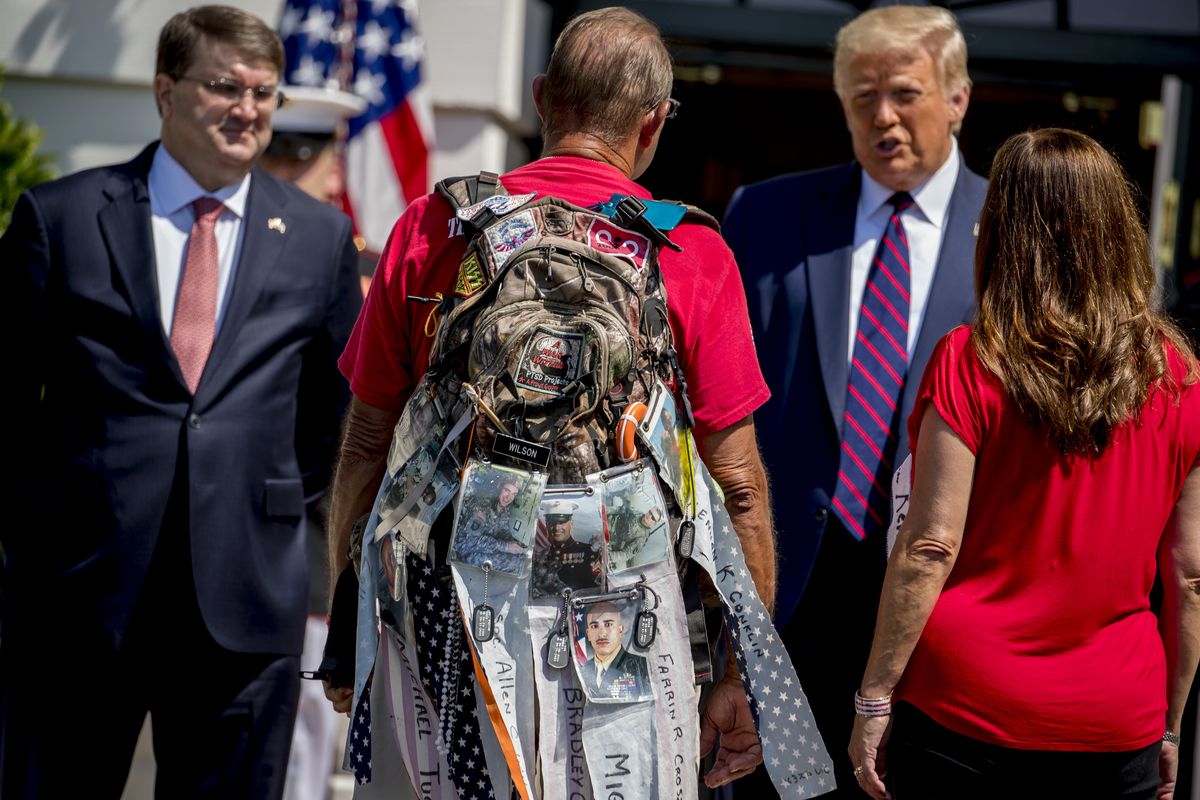 Photographs of soldiers are clipped to the backpack of Terry Sharpe, center, known as the "Walking Marine" as he is greeted by President Donald Trump, second from right, Veterans Affairs Secretary Robert Wilkie, left, and Karen Pence, the wife of Vice President Mike Pence, right, at the White House in Washington, Monday, July 27, 2020. Sharpe has walked from Summerfield, N.C., to Washington to raise awareness of the current veteran suicide rate.  (Andrew Harnik)