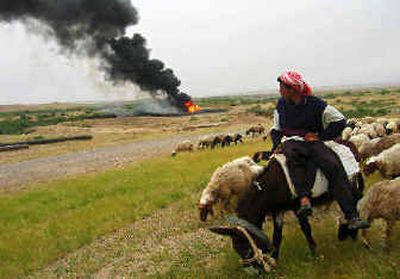 
A shepherd watches oil burn from a pipeline damaged by explosives west of Kirkuk, Iraq, on Monday. 
 (Associated Press / The Spokesman-Review)