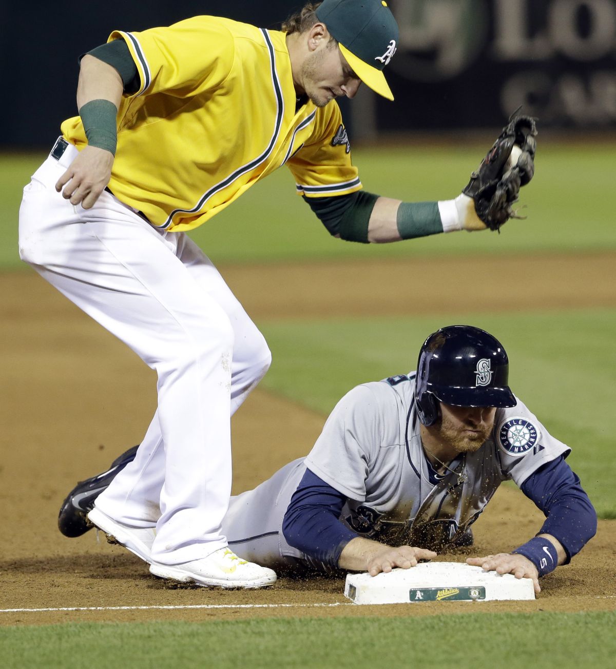 Seattle’s Brad Miller steals third base under the tag of Oakland third baseman Josh Donaldson. (Associated Press)